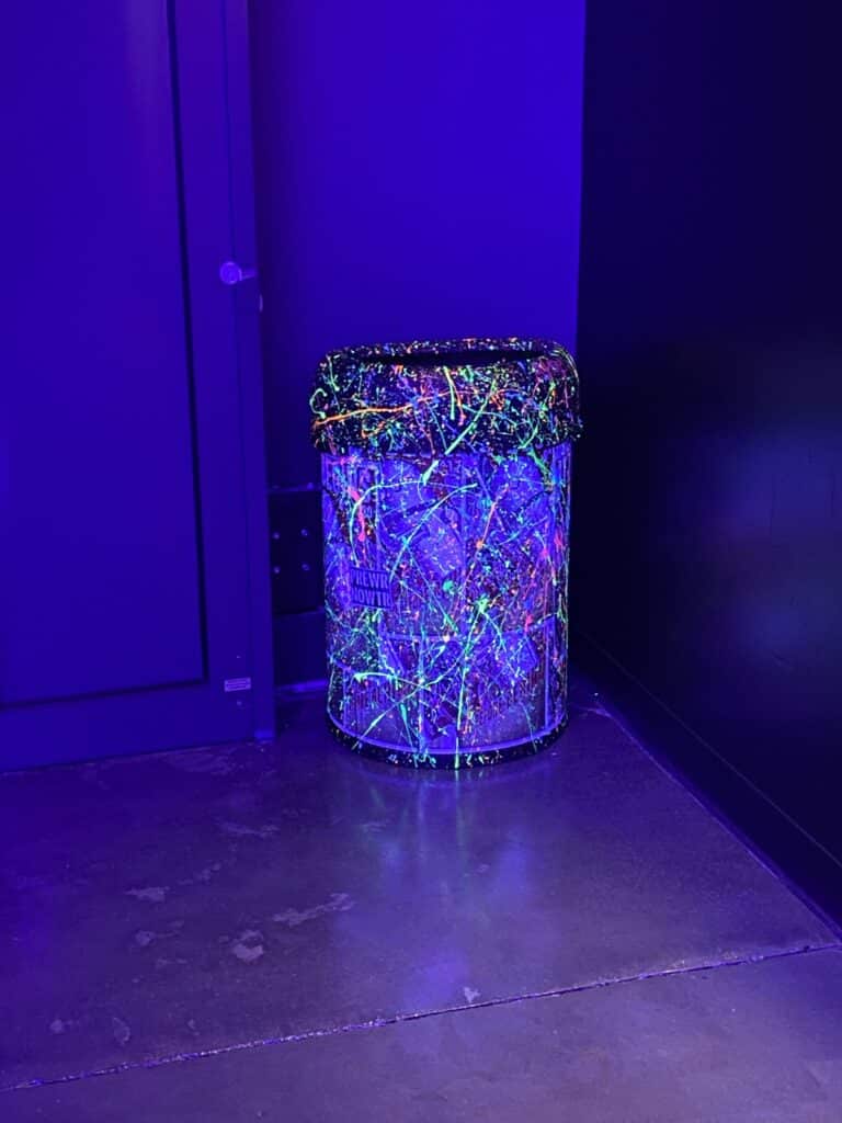 neon splattered paint trash can under UV lights