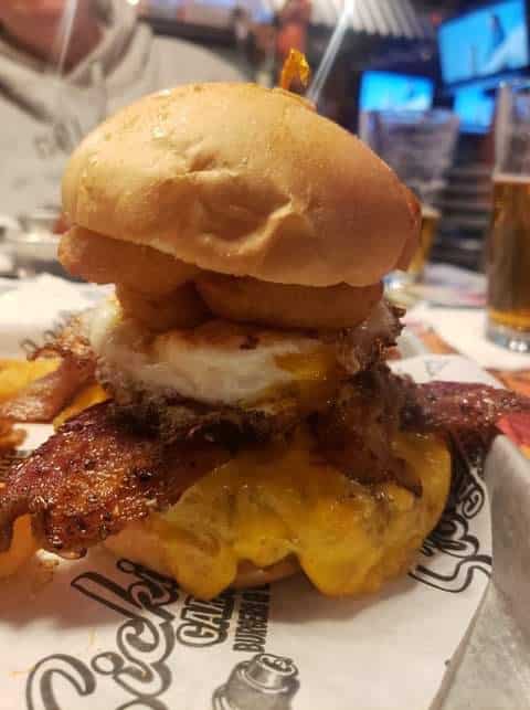 burger stacked with bacon, cheese, a fried egg, and onion rings from Sickie's Garage in Las Vegas