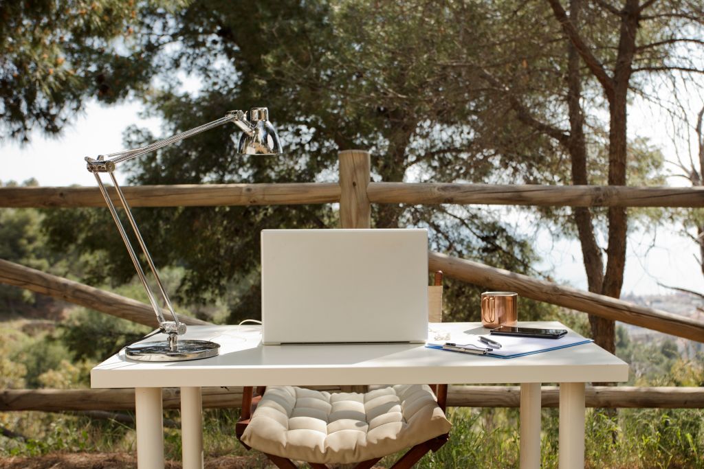 laptop on a desk on a back patio - tips for traveling on a budget - organize your travel documents before you leave