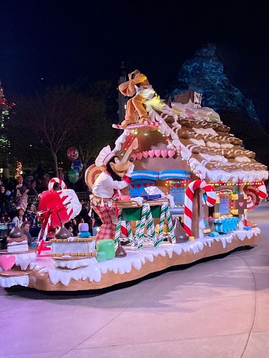 a parade float in Disneyland's Christmas parade with goofy and pluto on a gingerbread house