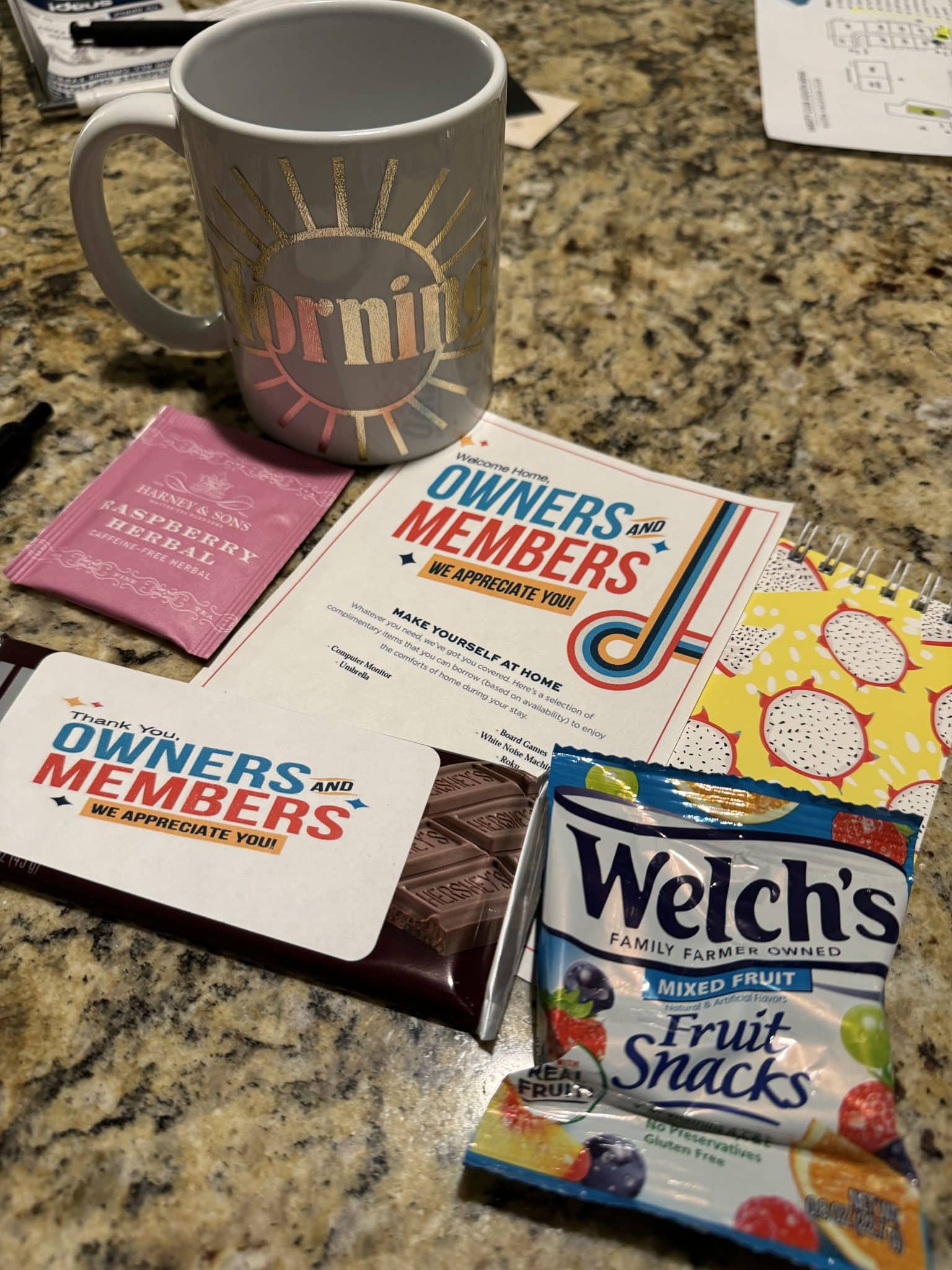 welcome package for owners and members with snacks, a coffee mug, and other trinkets